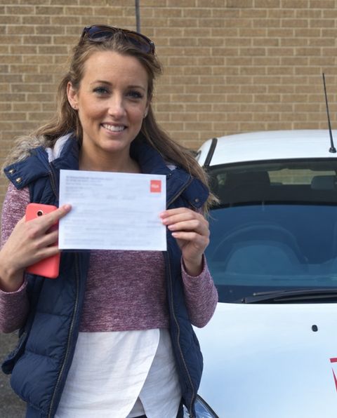 Learner with her pass certificate beside a white RSA School of Motoring car