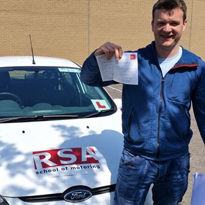 Learner holding his pass certificate beside an RSA School of Motoring car